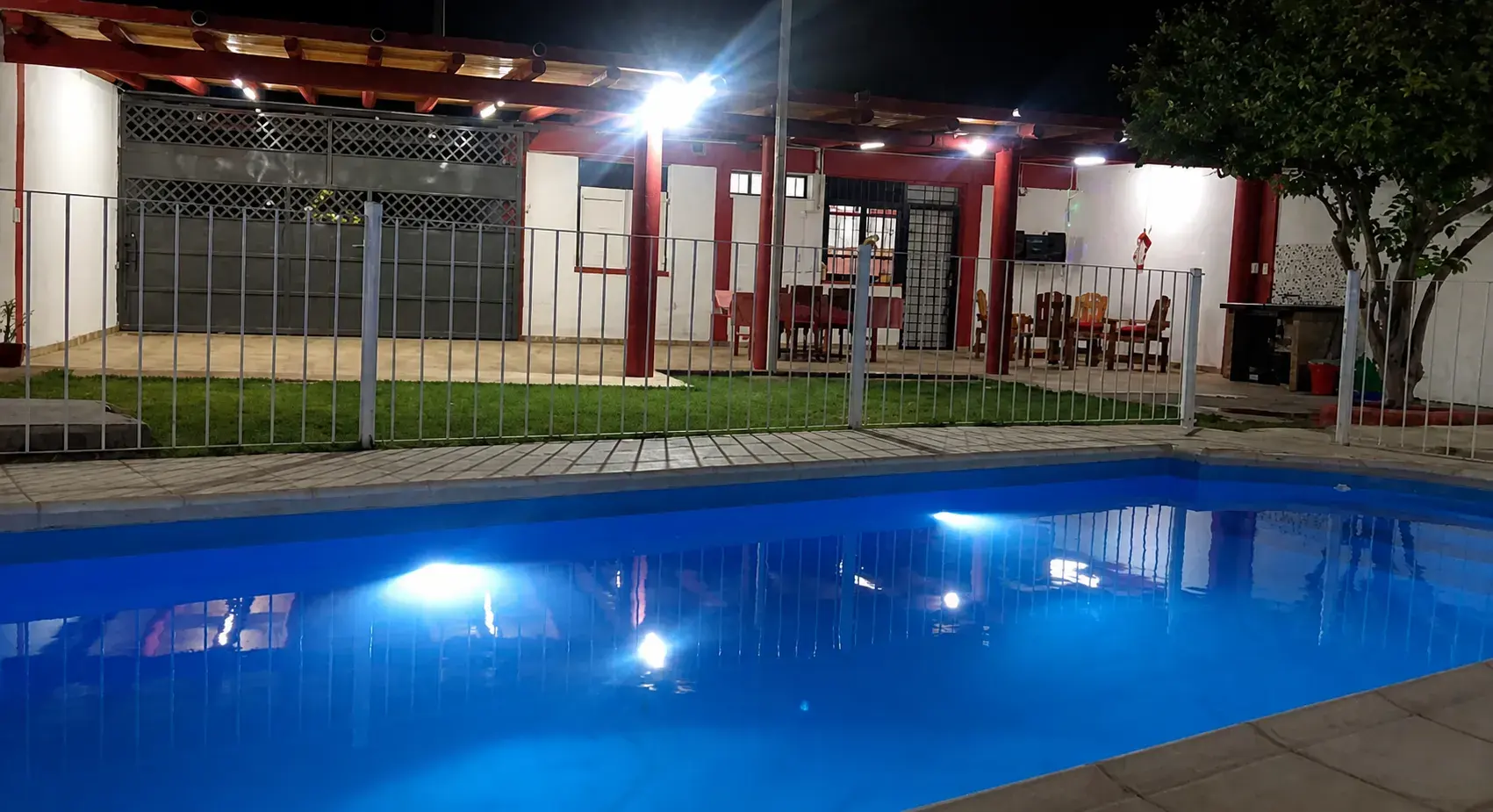 Pileta y galería techada de noche en Casa Pétalos Rojos